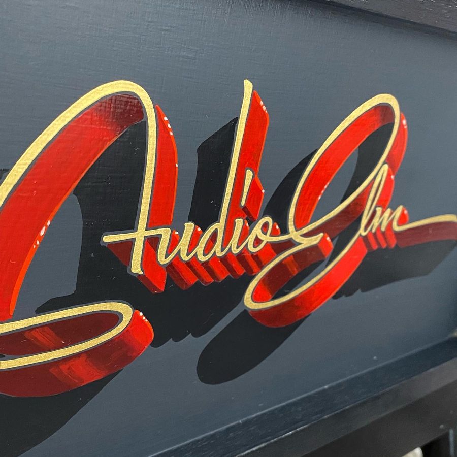 Audio Inc lettered in red and gold script on a dark grey panel