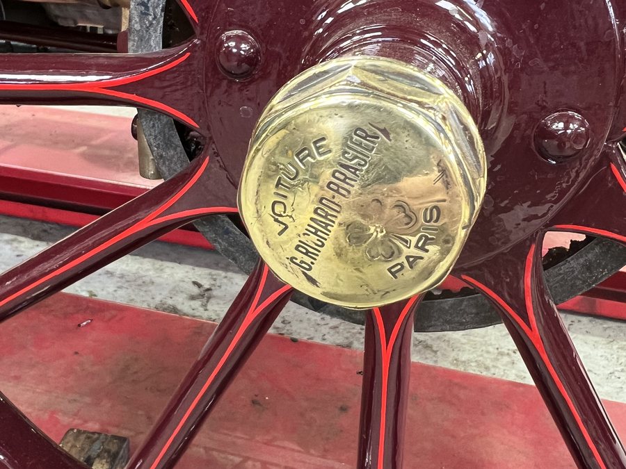 A gilded brass hub cap at the centre of a lined and pinstriped cartwheel