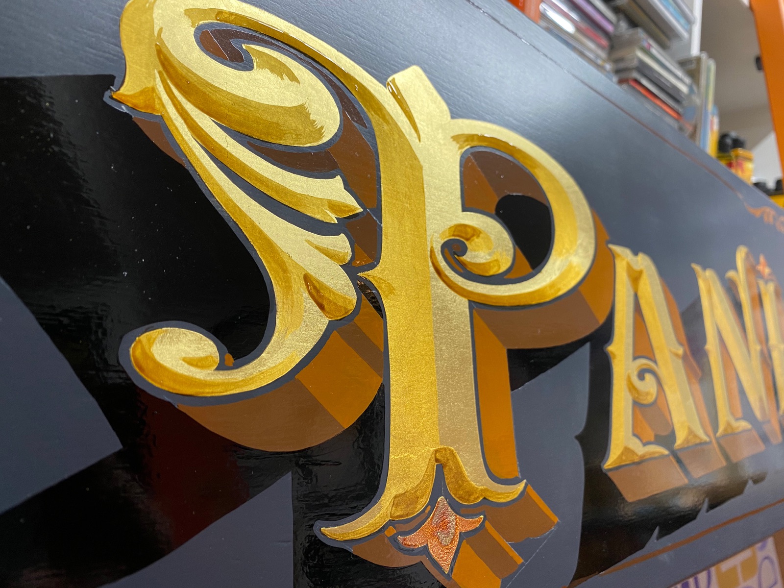 Hand-painted gold leaf lettering on a traditional sign